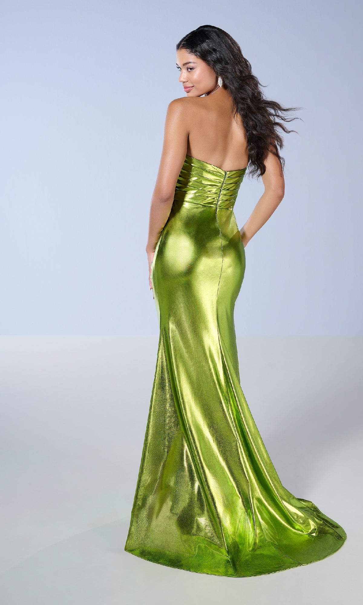 A woman models the Long Prom Dress: Tiffany 16152, a shiny lime green strapless gown with an elegant silhouette, standing with her back to the camera and glancing over her shoulder.